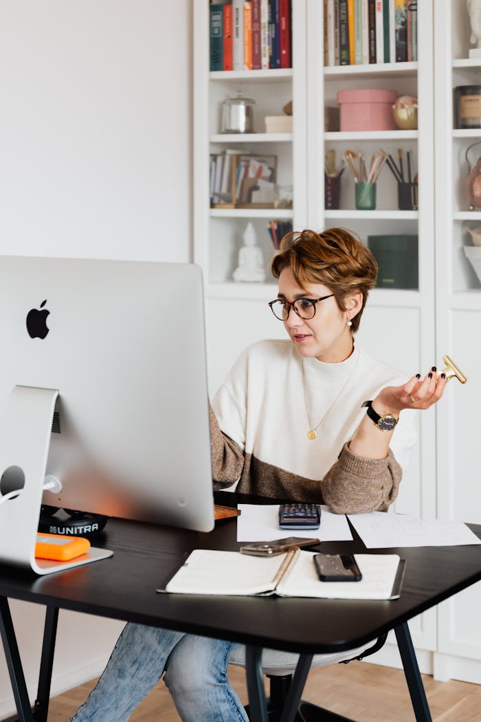 Focused businesswoman engaging in a video call while planning a project at her modern office desk.